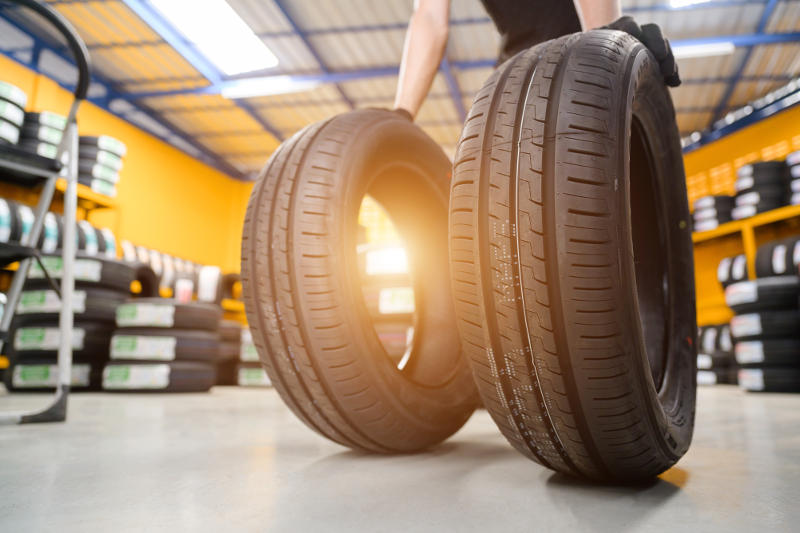 Mechanic holding two tires of different sizes side by side.